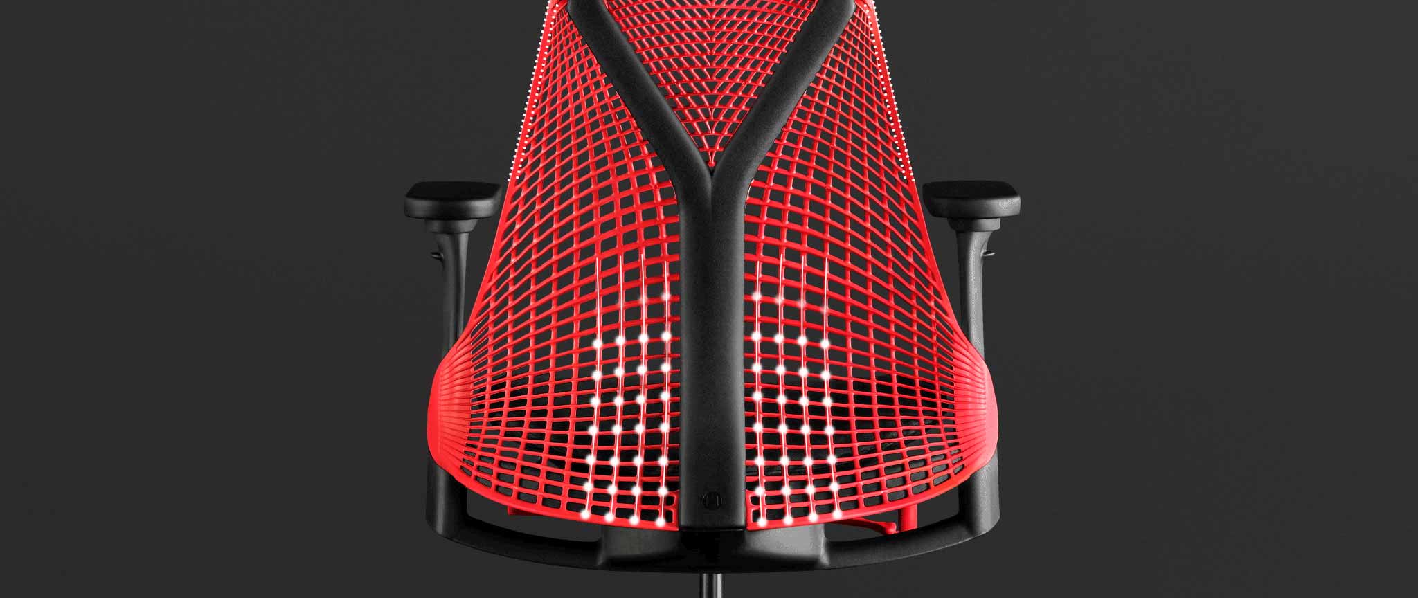 Vista trasera de una silla de juego Sayl roja y negra de Herman Miller, superpuesta con gráficos blancos que resaltan el respaldo con suspensión.