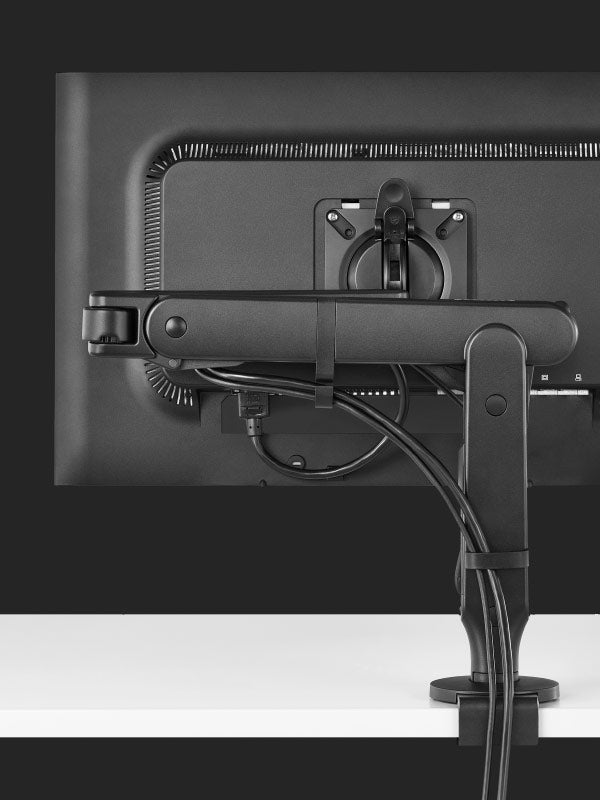 Vista trasera de un brazo para monitor de juego Ollin negro de Herman Miller, que muestra la función de gestión de cables.