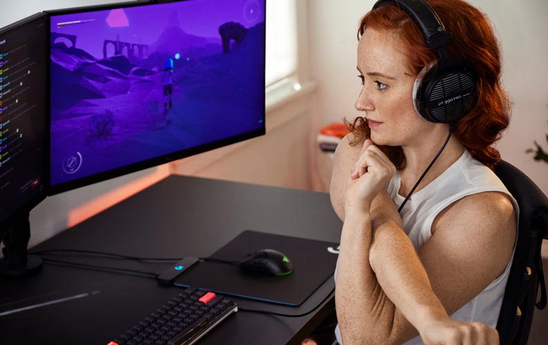 La doctora en deportes electrónicos Lindsey Migliore delante de una configuración para gaming con dos monitores en brazos para monitor Ollin.