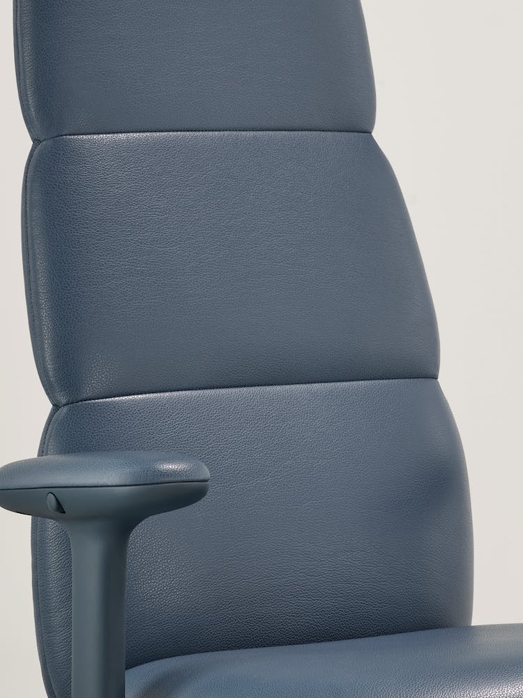 Primer plano de una silla de oficina Asari de piel azul de Herman Miller, que muestra la tecnología Posturefit integrada e interna.