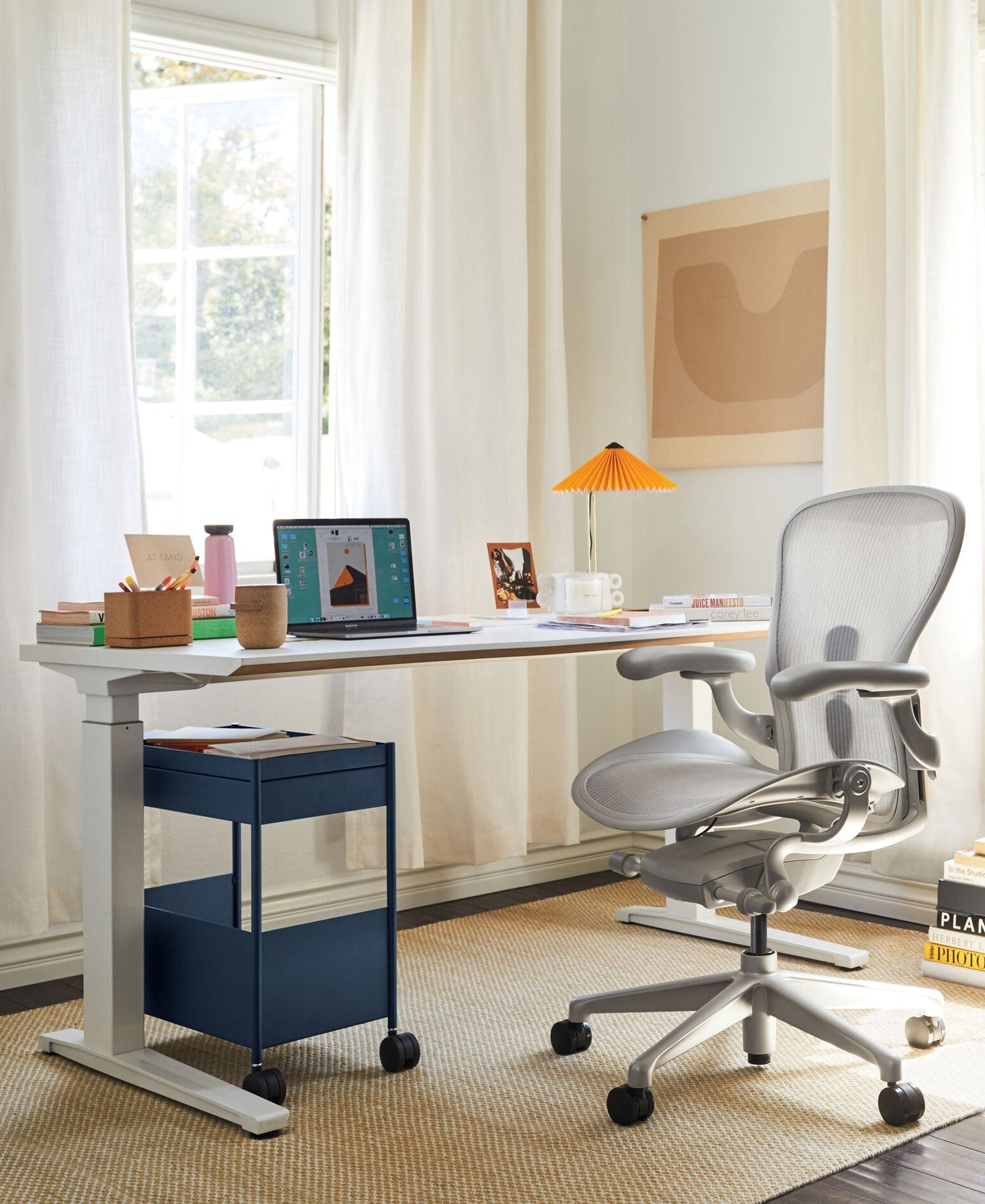 Oficina en casa con silla de oficina Aeron en blanco mineral, con escritorio sit-stand Jarvis en blanco y accesorios que incluyen un soporte para portátil Oripura y una lámpara de mesa Hay Matin