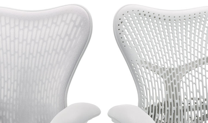 Dos sillas de oficina Mirra 2 blancas de Herman Miller, colocadas una al lado de la otra. Mostrando las dos opciones de respaldo, una con una capa adicional de tela y otra sin ella.