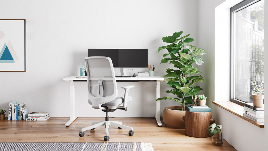 Un escritorio blanco Nevi Sit Stand de Herman Miller como parte de una oficina doméstica luminosa.