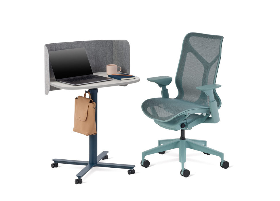 Una silla de oficina Cosm azul de Herman Miller colocada junto a una mesa Passport azul y blanca de Herman Miller.