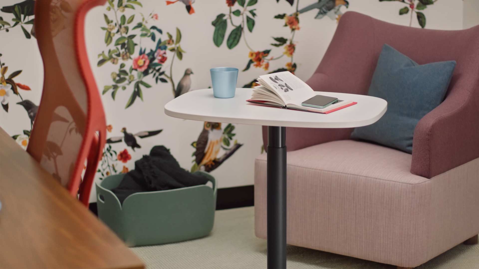 Un vídeo de una mujer sentada en un sillón Wilkes amarillo utilizando una mesa Passport de Herman Miller. El vídeo continúa mostrando el uso de la mesa Passport en diversos lugares, tanto en oficinas como en entornos domésticos.
