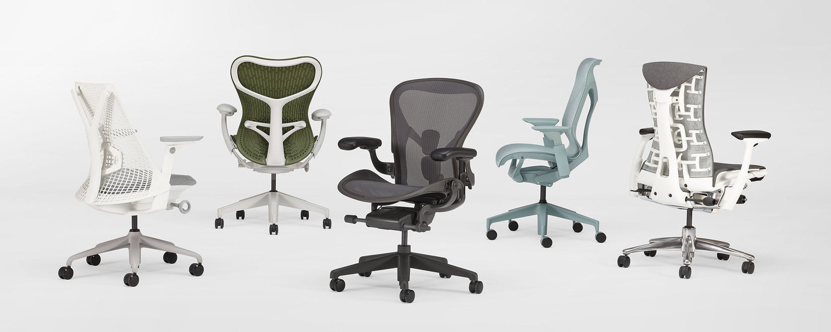 Selección de 5 sillas de oficina ergonómicas de Herman Miller en un estudio de color blanco. Incluye los modelos Sayl, Mirra 2, Aeron, Cosm y Embody.