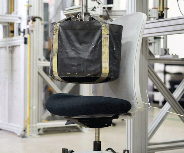 Foto de la prueba de caída, que muestra el peso que se deja caer sobre el cojín del asiento de la silla, a la que se someten todas las sillas Herman Miller.