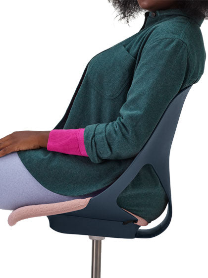 Vista lateral de una persona sentada en una silla de oficina Zeph azul de Herman Miller con cojín de asiento rosa.