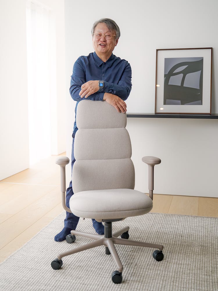 El diseñador, Naoto Fukasawa, apoyado en una silla de oficina Asari de Herman Miller. Al fondo, el suelo y la pared limpios.