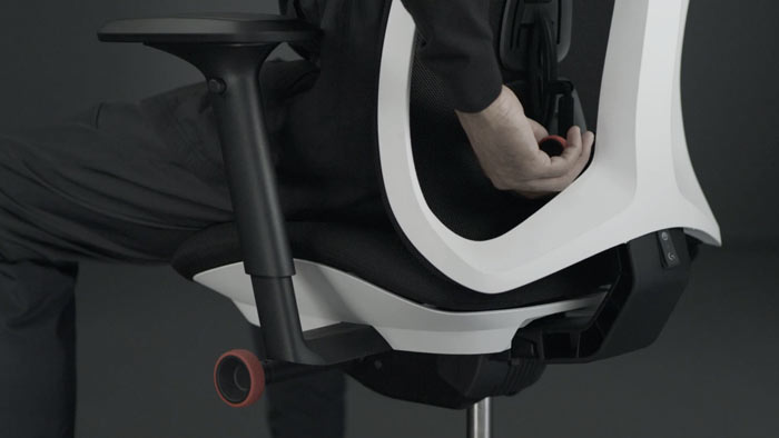 Vídeo de una persona sentada en una silla de juego Vantum blanca y negra de Herman Miller, extendiendo la mano por detrás de la silla para ajustar el respaldo.