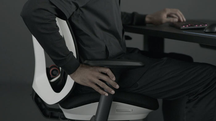 Vídeo de una persona sentada en una silla de juego Vantum blanca y negra de Herman Miller, extendiendo la mano junto a la silla para ajustar los brazos.