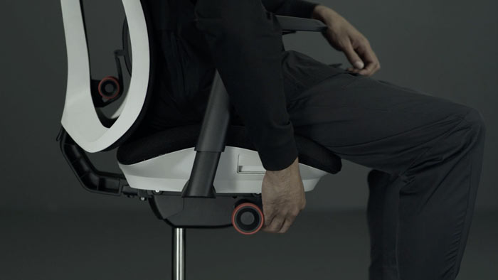 Vídeo de una persona sentada en una silla de juego Vantum blanca y negra de Herman Miller, acercándose a la silla para ajustar la altura del asiento.