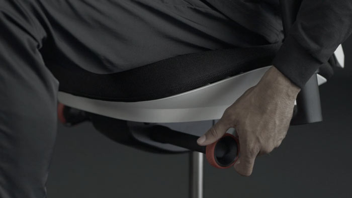 Vídeo de una persona sentada en una silla de juego Vantum blanca y negra de Herman Miller, acercándose a la silla para ajustar el limitador de inclinación.