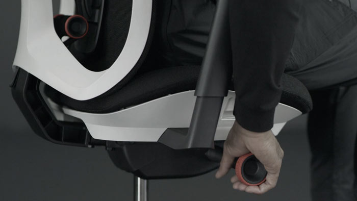 Vídeo de una persona sentada en una silla de juego Vantum blanca y negra de Herman Miller, acercándose a la silla para ajustar la tensión de inclinación.