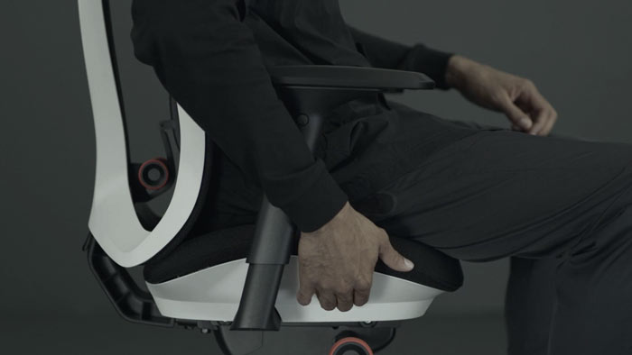 Vídeo de una persona sentada en una silla de juego Vantum blanca y negra de Herman Miller, acercándose a la silla para ajustar la profundidad del asiento.