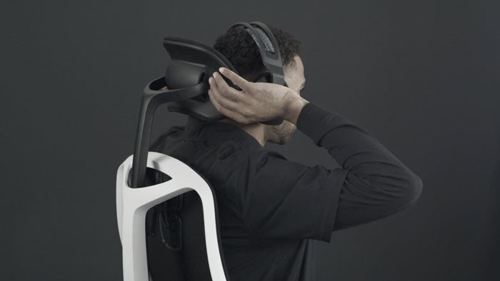 Vídeo de una persona sentada en una silla de juego Vantum blanca y negra de Herman Miller, extendiendo la mano detrás de la silla para ajustar el reposacabezas.