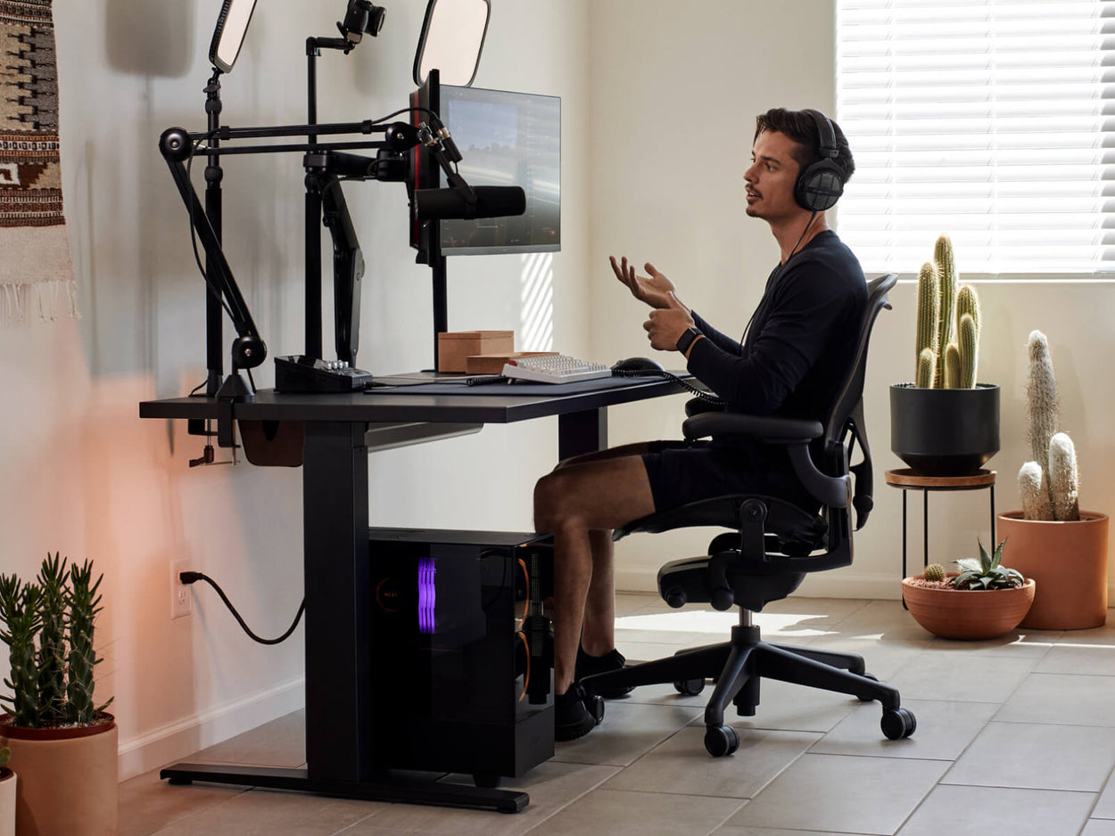 El jugador Xaryu sentado en su equipo de juego en casa con una silla para juegos Aeron en color grafito, un escritorio para juegos Nevi y brazos para dos monitores Ollin