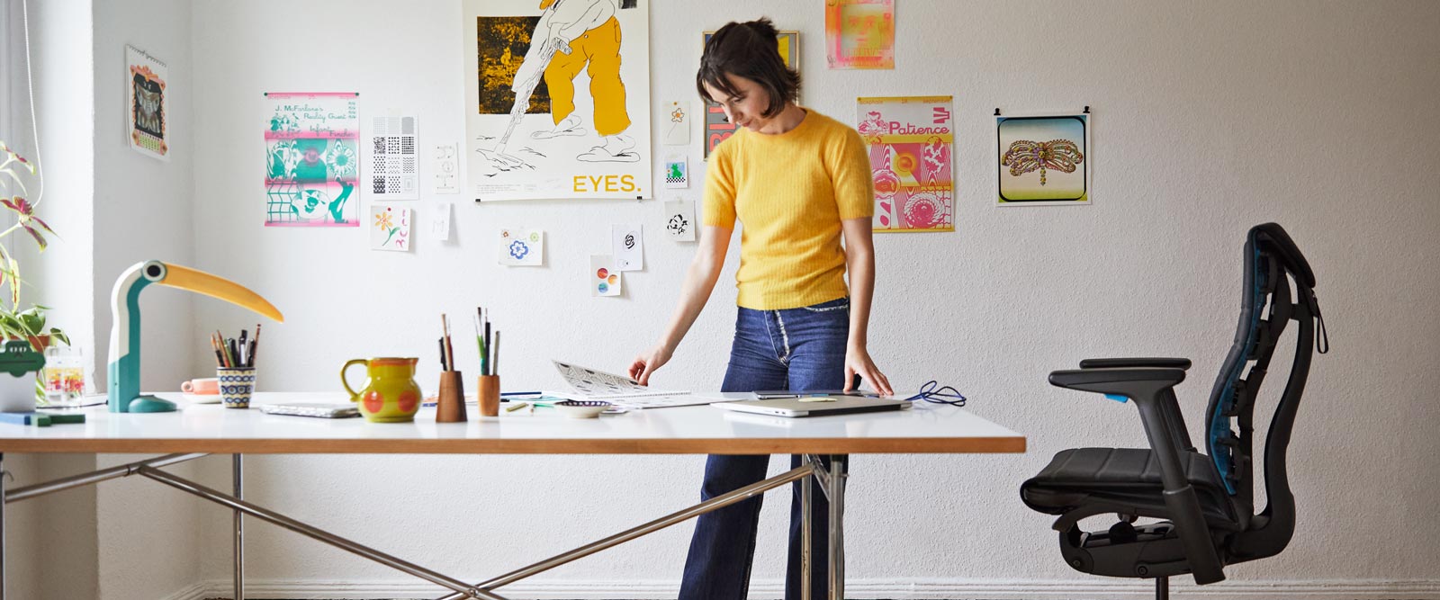 La ilustradora, pintora y autora Molly Rose Dyson de pie en su estudio, con una silla gaming Embody en negro y azul cian