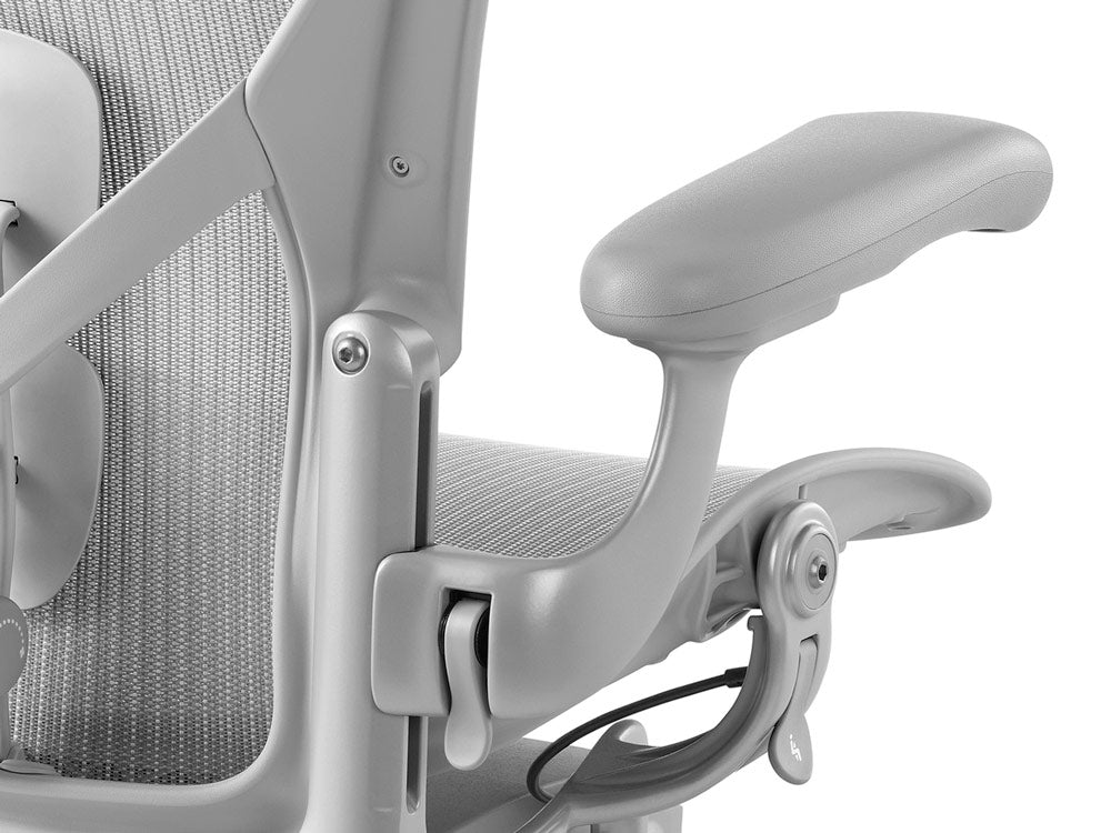 Primer plano de la silla Aeron en mineral, vista desde atrás, mostrando las palancas de ajuste de los reposabrazos y el asiento.