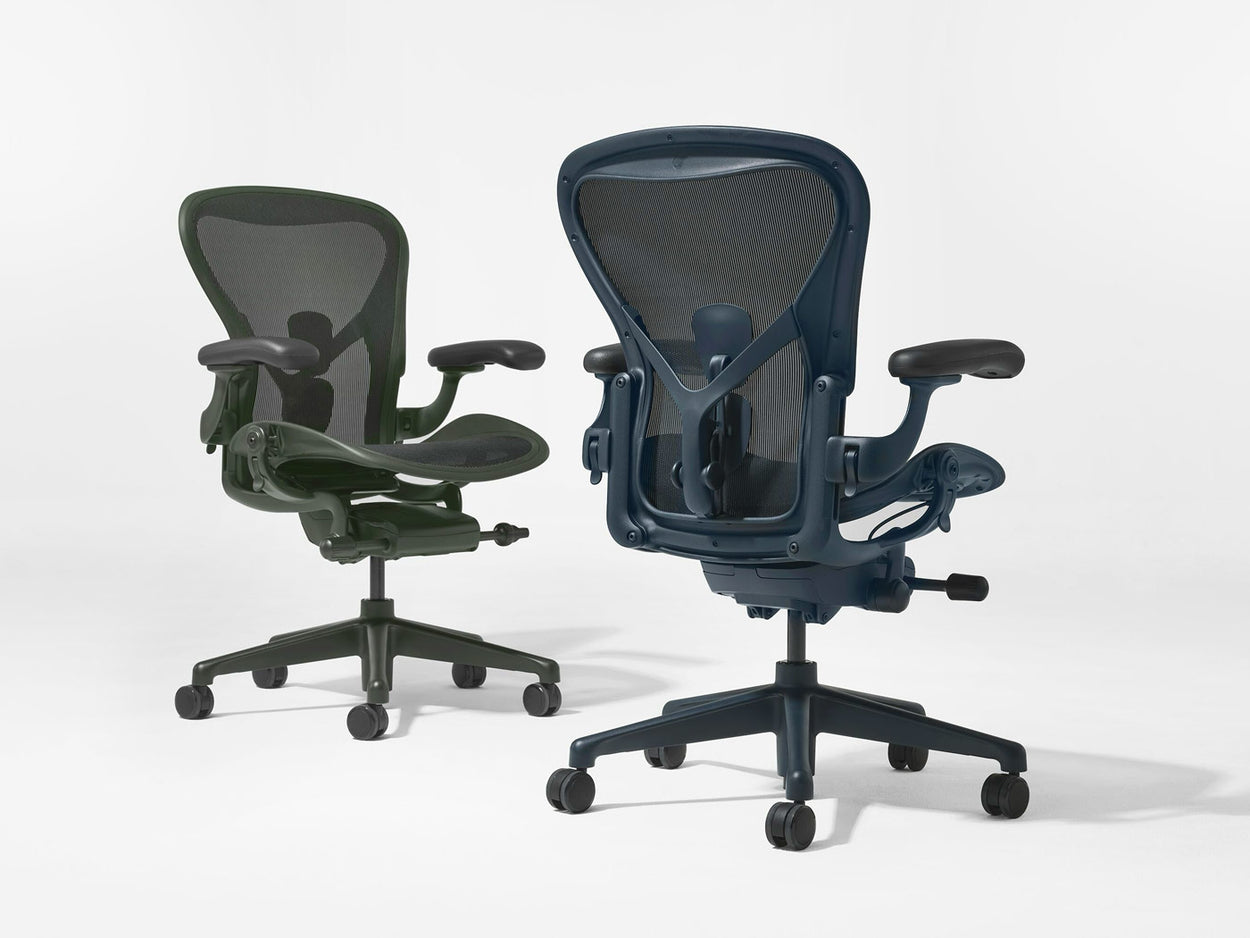 Dos sillas de oficina Herman Miller Aeron en verde Jasper y azul Nightfall fotografiadas en un estudio blanco.