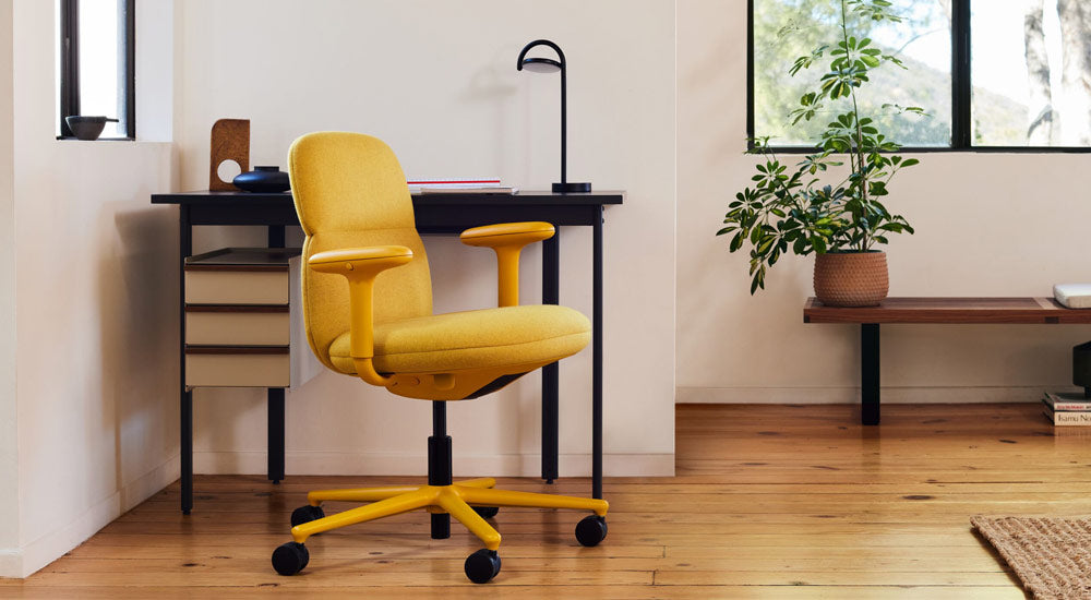 Una silla de oficina Asari amarilla de Herman Miller, tapizada en tela Clarion Luce de Maharam, con un escritorio Mode y una lámpara Marselis.