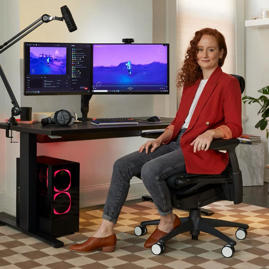 La doctora en deportes electrónicos Lindsey Migliore delante de un equipo gaming con dos monitores en brazos para monitor Ollin.