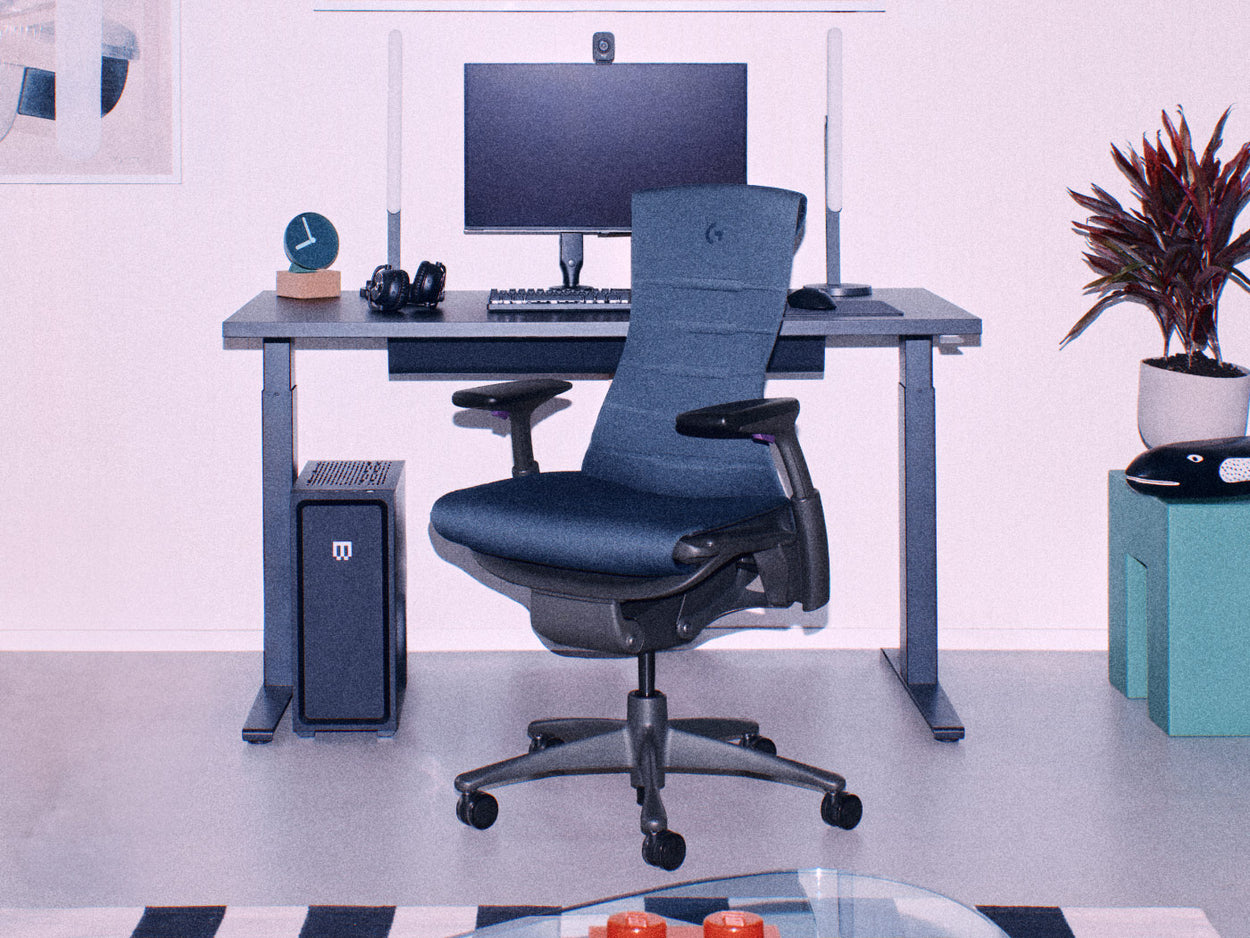 Silla gaming Embody negra de Herman Miller con escritorio gaming Nevi negro para sentarse y estar de pie con configuración gaming que incluye dos monitores