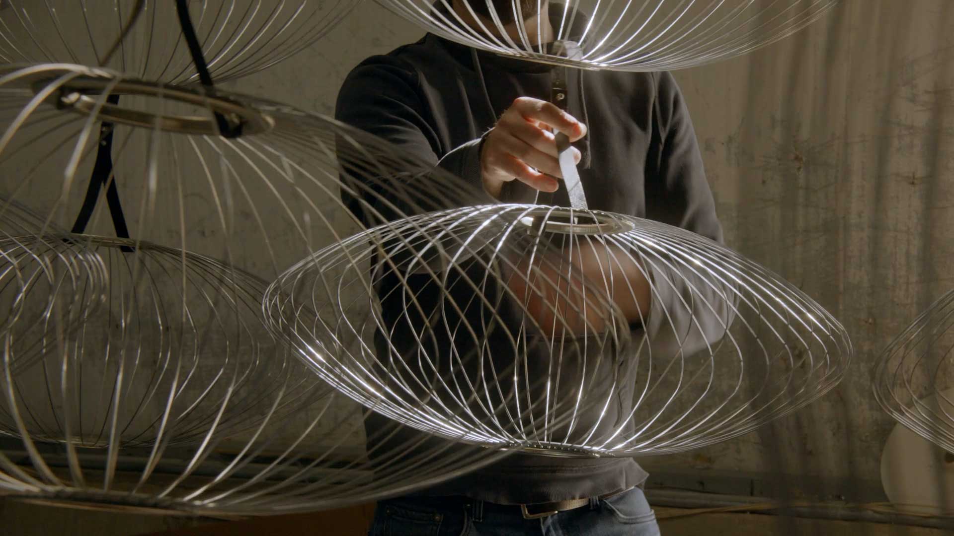 Un trabajador cualificado elaborando las estructuras de alambre de una selección de pantallas de lámparas Nelson Bubble.