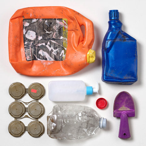 Fotografía de diversos artículos de plástico recuperados de los océanos del mundo, incluyendo botellas y tapas.