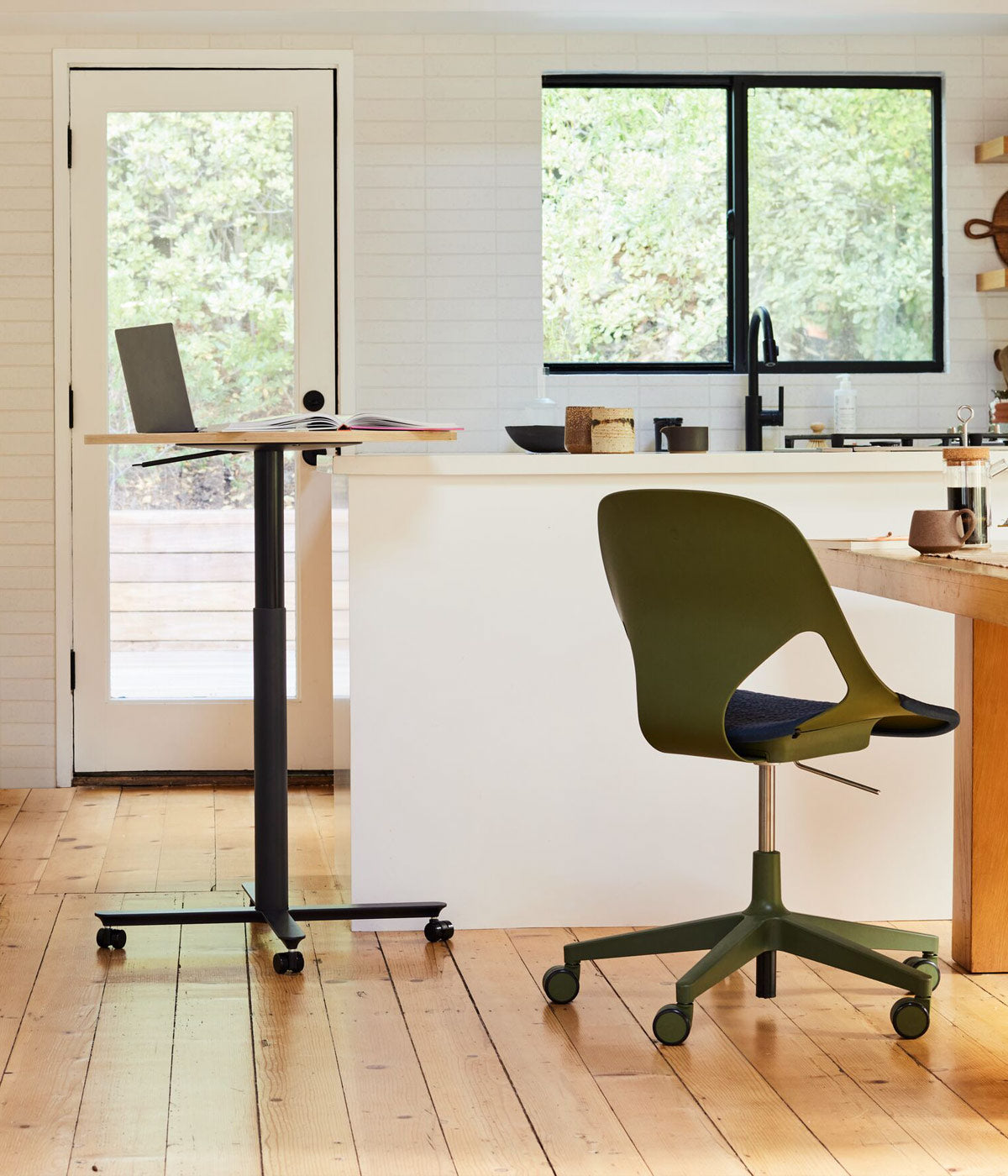 Escenario de oficina en casa en la cocina con mesa de trabajo sit-stand Passport con tablero de roble y una silla de oficina Zeph en oliva con cojín para el asiento en azul noche en la mesa de la cocina