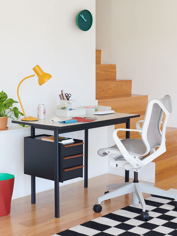 Oficina en casa con escritorio de altura fija Mode con cajones y silla de oficina Cosm de respaldo bajo en blanco con varios accesorios de oficina.