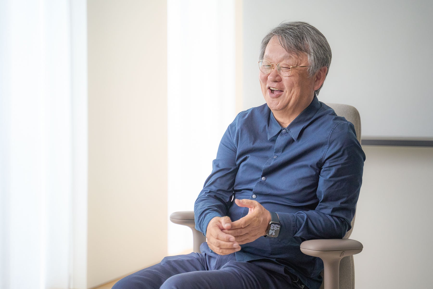 Fotografía alegre de Naoto Fukasawa sentado en una silla de oficina Asari