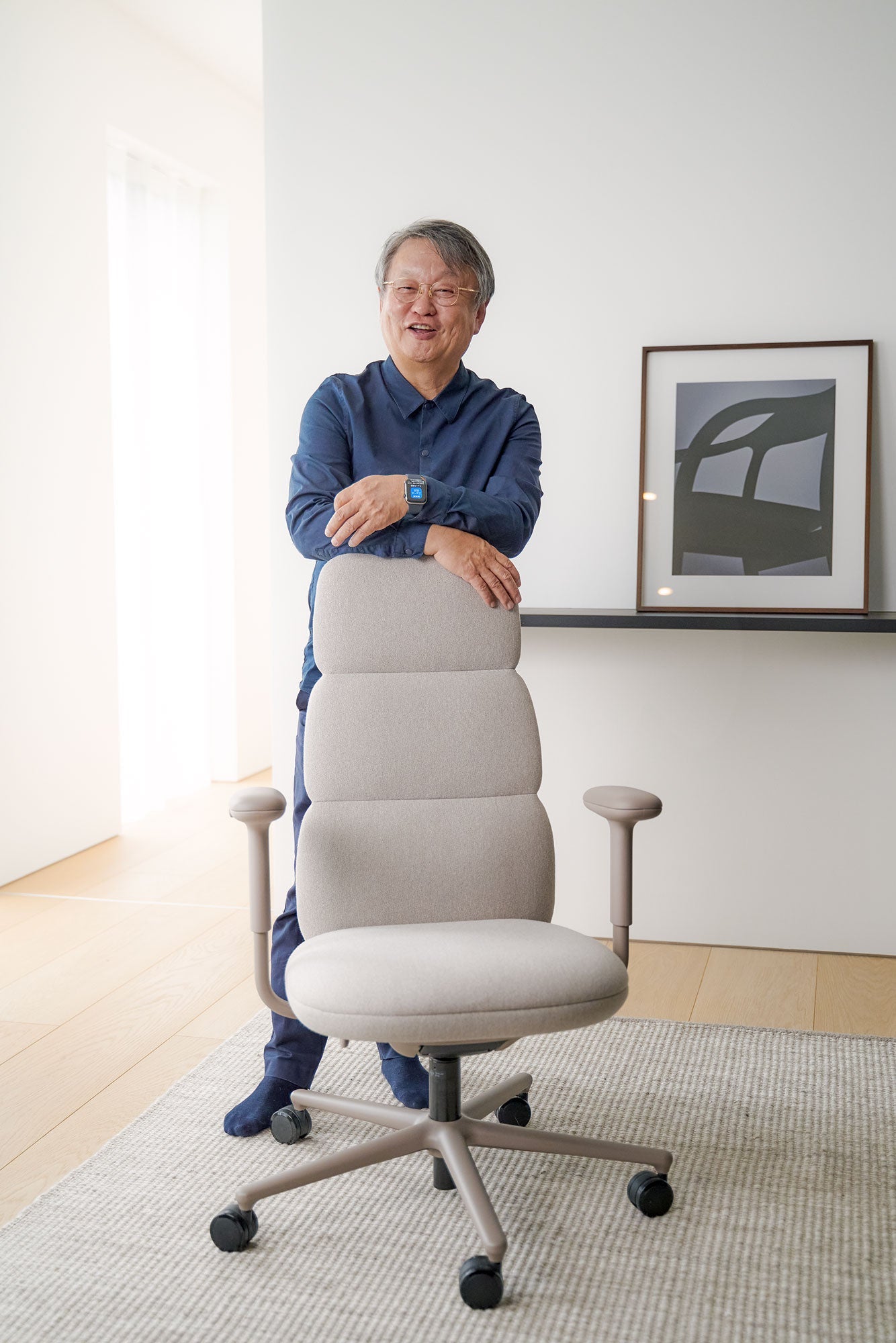 Fotografía de Naoto Fukasawa de pie detrás de una silla de oficina Asari en color blanco alpino