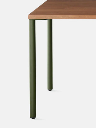 Primer plano del extremo de un escritorio OE1 de madera con patas de color verde oliva.