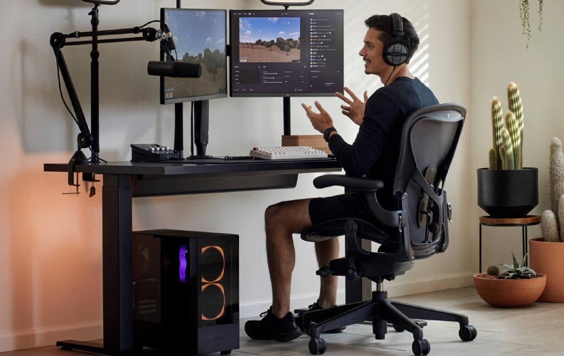 El jugador y streamer Xaryu en un equipo gaming sentado en una silla gaming Herman Miller Aeron con un escritorio gaming sit-stand Nevi negro y dos monitores en brazos para monitor Ollin